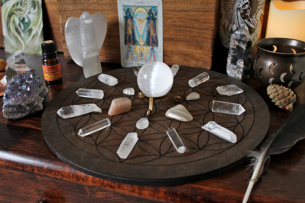 Full Moon crystal grid with Selenite sphere, candles, tarot card, feather and essential oils