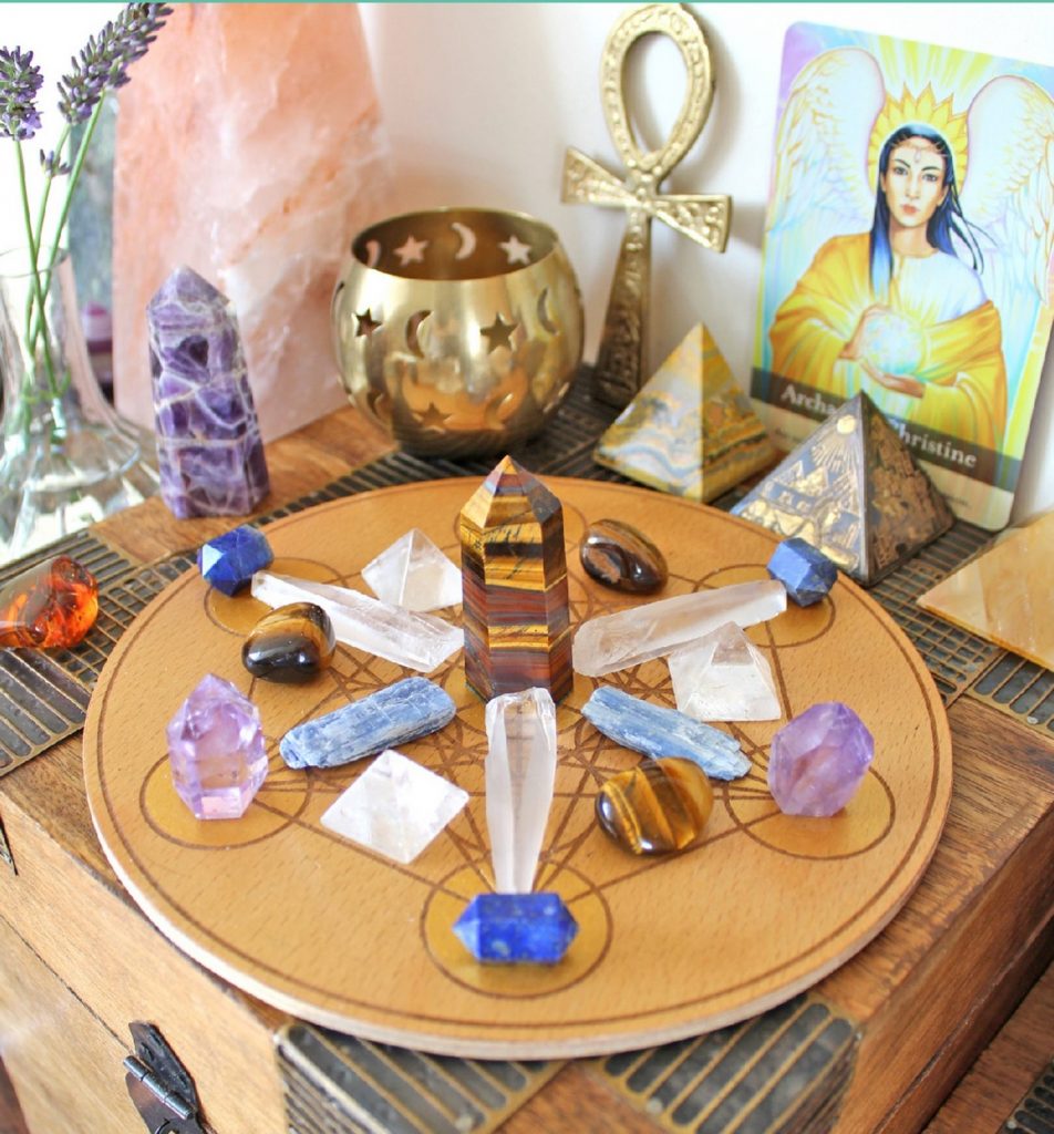 Crystal Grid on an altar with candle, ankh, angel oracle card, crystal pyramids, lavender flowers in a vase